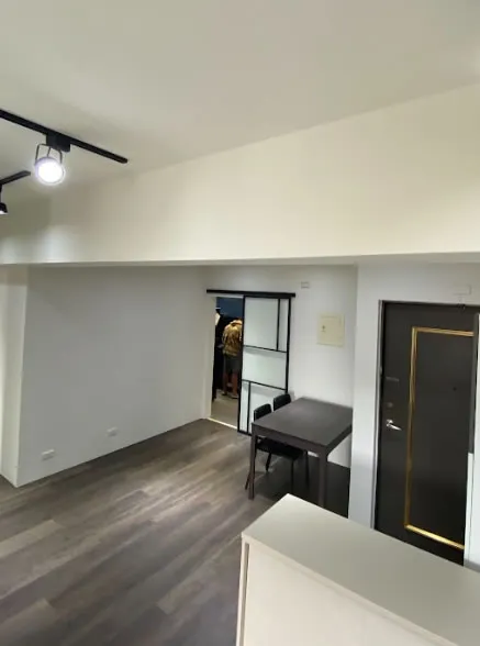 完工的餐廳區，深色餐桌椅靠近黑框玻璃滑門，右側為大門